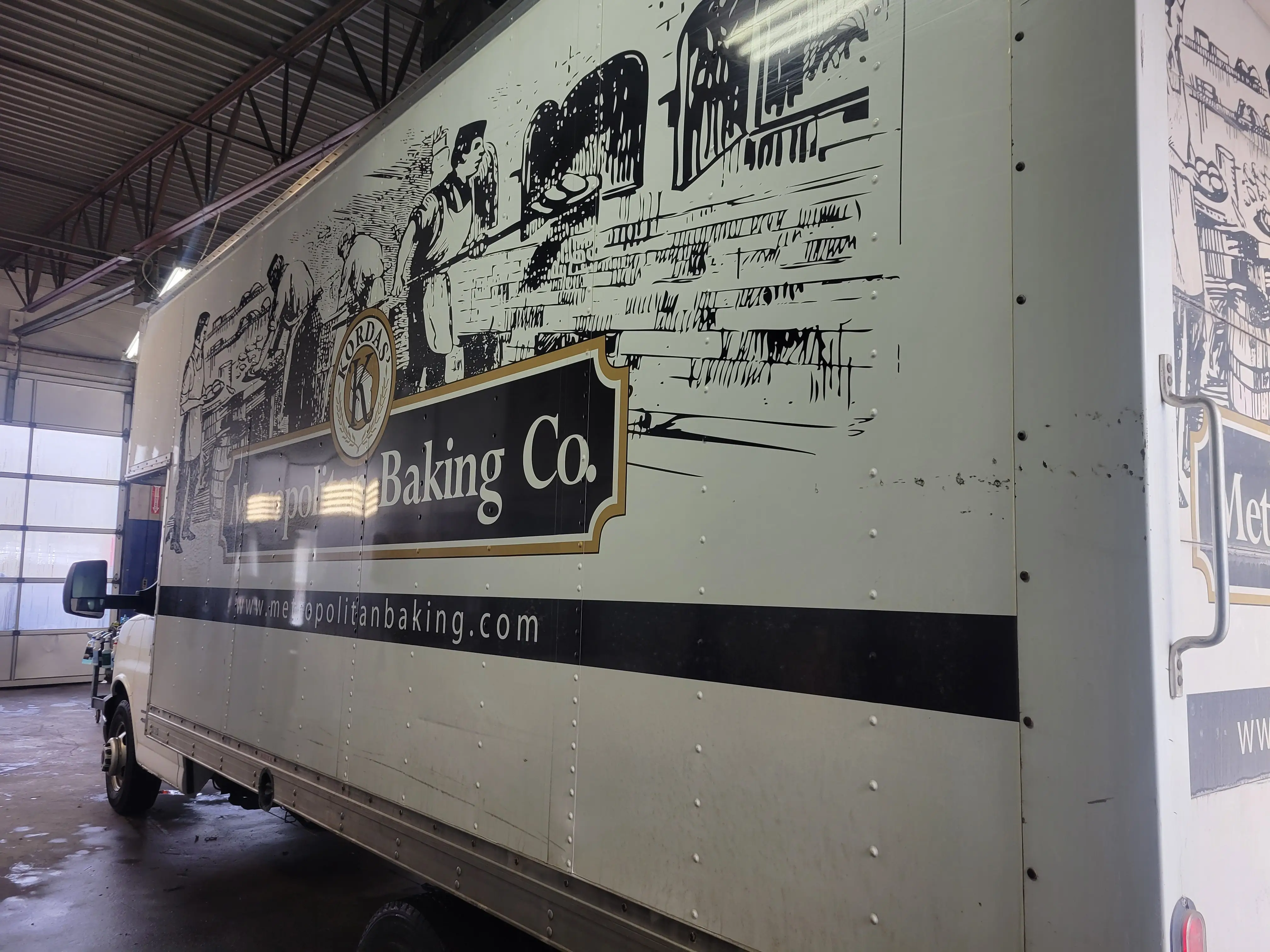 A box truck carrying a full vinyl graphics wrap before removal at Fast Track Detailing Solutions in Oakland County, Michigan