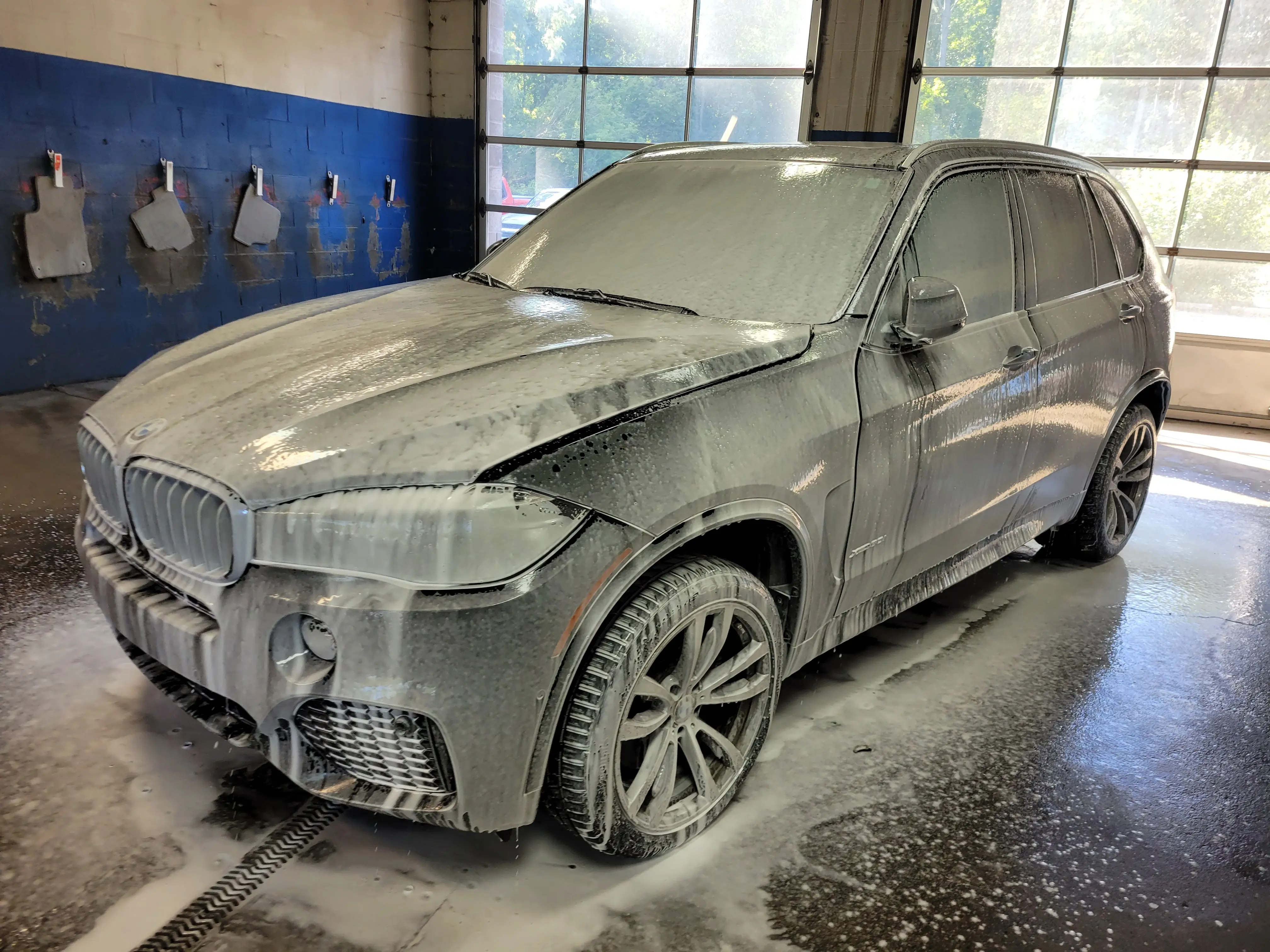 A BMW X5 caked in winter road salt and grime, before detailing at Fast Track Detailing Solutions in Oakland County, Michigan